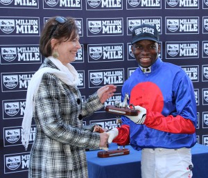 Former Champion jockey S'manga Khumalo in Chris Van Niekerk's colours receives his winning trophy from Linda Norval. Image: Candiese Marnewick